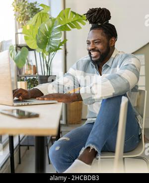 Hipster man laughing and using laptop at home Stock Photo