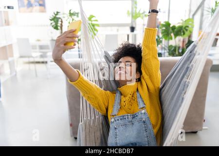 Woman laughing by hipster man on swing at home Stock Photo