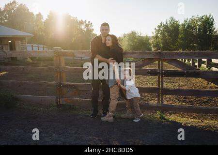 Family hugging each other at horse farm on sunny day Stock Photo