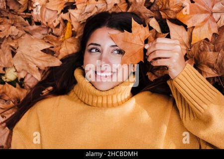 Smiling woman holding dry maple leaf Stock Photo