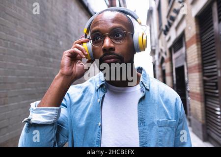 Man with wireless headphones in alley Stock Photo