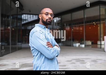 Man with shaved head standing near buildings Stock Photo