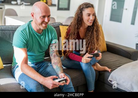 Smiling couple playing video games at home Stock Photo