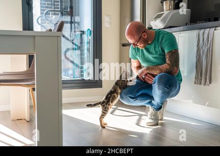 Man playing with cat at home Stock Photo