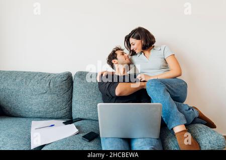 Smiling young couple looking at each other while working at home Stock Photo