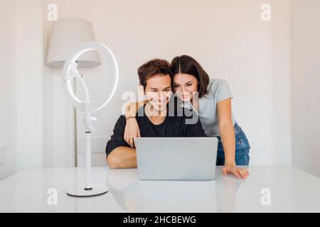 Smiling young couple using laptop together on table at home Stock Photo