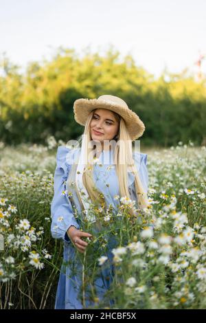 Thoughtful woman holding flowers in meadow Stock Photo