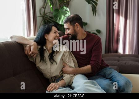 Smiling woman sitting with man on sofa Stock Photo