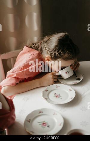 Girl drinking tea in cup on table at home Stock Photo