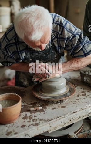 Close-up of senior potter modeling the vase from clay on pottery wheel in workshop Stock Photo