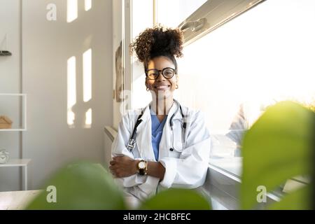 Thoughtful female doctor looking out of window at home Stock Photo