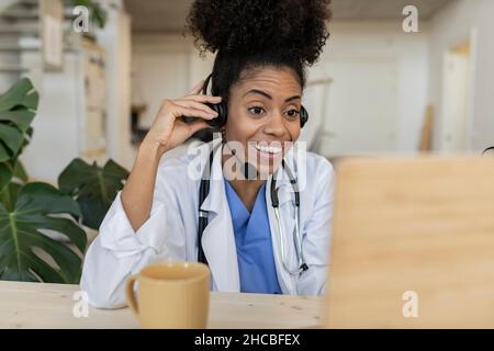 Doctor with talking through headphones at home office Stock Photo