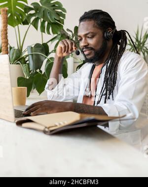 Happy hipster doctor talking on mobile phone sitting with laptop at home office Stock Photo