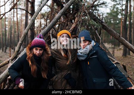 Friends wearing warm clothing in front of log shelter Stock Photo