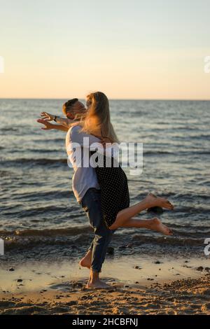 Playful man picking up woman at water's edge Stock Photo