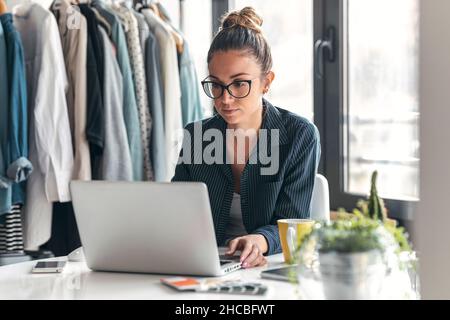 Young fashion designer using laptop at desk Stock Photo