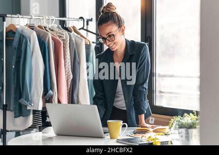 Smiling fashion designer using laptop in office Stock Photo