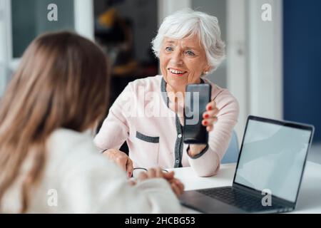 Woman looking at girl using laptop on table Stock Photo