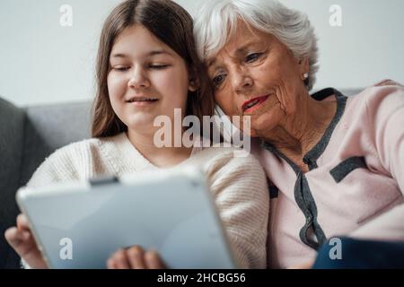 Woman showing mobile phone to girl with laptop at table Stock Photo
