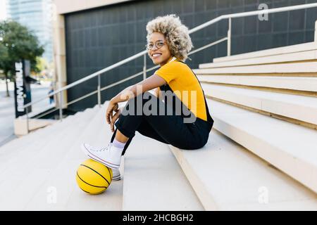 Woman with yellow basketball sitting on steps Stock Photo