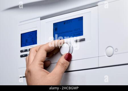 Cropped hand of woman adjusting knob on heating boiler's control panel Stock Photo