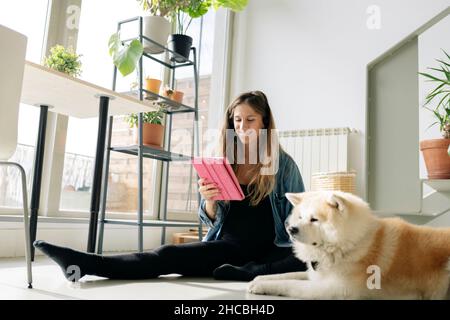 Pregnant woman using digital tablet by dog at home Stock Photo