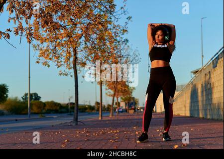 Athlete with arms raised stretching on footpath Stock Photo