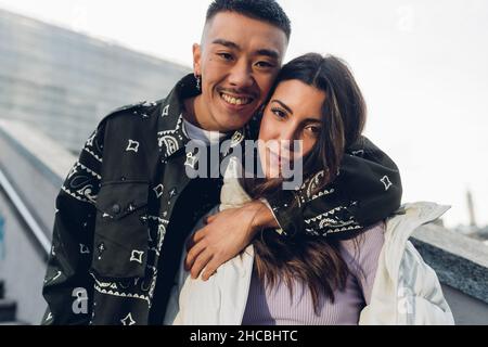 Smiling young man with arm around girlfriend Stock Photo