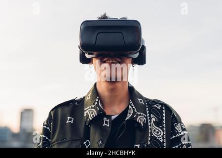 Smiling man wearing virtual reality headset in city Stock Photo