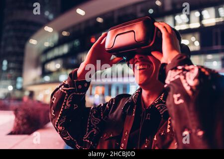 Young man using virtual reality headset at night in city Stock Photo