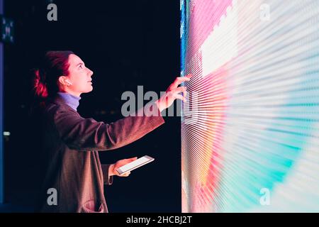 Businesswoman using touch screen interactive information booth at night Stock Photo