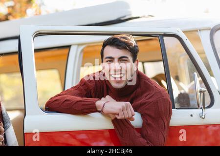 Happy young man leaning on door of van Stock Photo