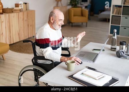 Disabled businessman with coffee cup using laptop at home office Stock Photo