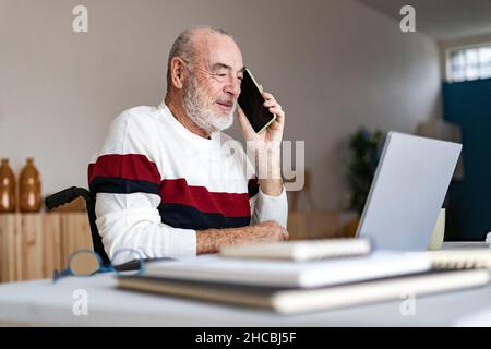 Senior businessman talking on mobile phone at home office Stock Photo