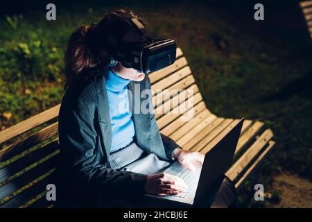 Businesswoman using laptop wearing virtual reality headset Stock Photo