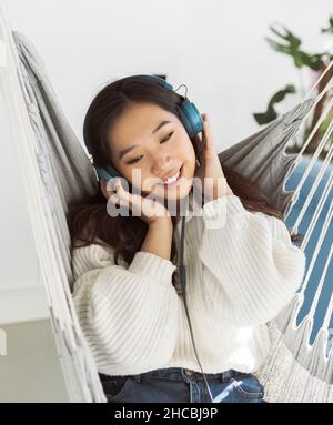 Smiling young woman wearing headphones in hammock Stock Photo