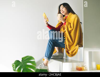 Young woman watering houseplant in living room Stock Photo