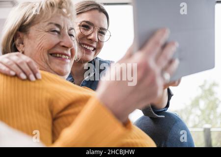 Smiling women using tablet PC at home Stock Photo