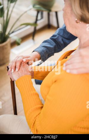Senior woman and caregiver stacking hands at home Stock Photo