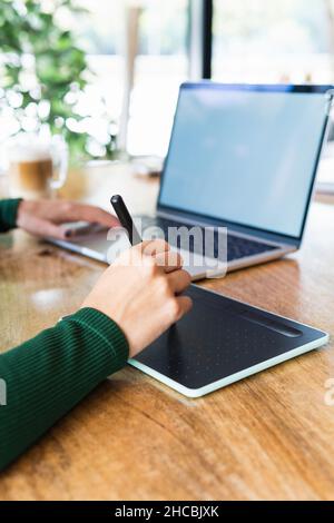 Businesswoman with laptop using graphics tablet at cafe Stock Photo