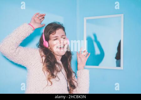 Happy woman enjoying music by mirror Stock Photo