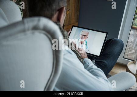 Doctor advising patient on video call through tablet PC at home Stock Photo