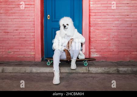 Woman wearing dog mask sitting on longboard in front of closed blue door Stock Photo