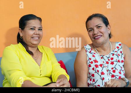 Two sisters sitting together on the sofa at home Stock Photo