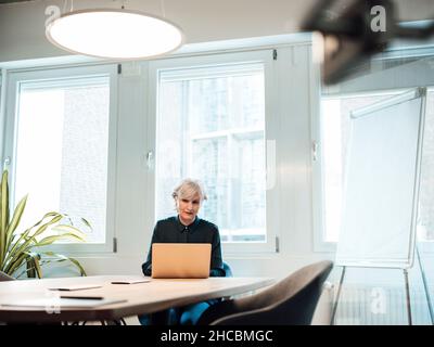Senior businesswoman writing on note pad at desk Stock Photo