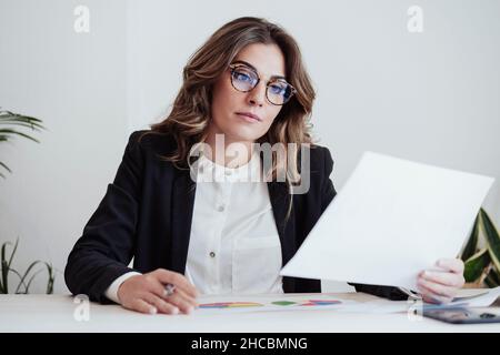 Focused businesswoman looking at document in office Stock Photo