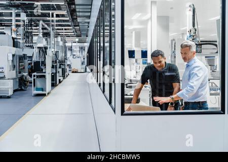 Businessman explaining strategy on laptop to engineer in factory Stock Photo