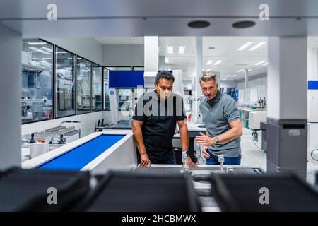 Engineer explaining machinery to colleague in factory Stock Photo