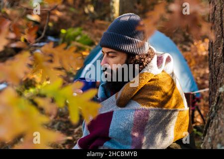 Bearded man drinking coffee in mug at autumn forest Stock Photo