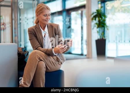 Thoughtful businesswoman sitting with legs crossed at knee in office Stock Photo